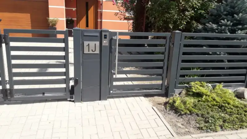 Furtka z numerem domu przy słupku z bloczków na tle nawierzchni z kostki