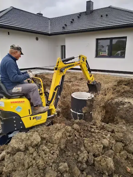 Minikoparka wykonująca wykop pod fundament ogrodzenia